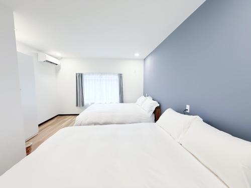 two beds in a white room with a window at Osaka Large House 13Guests 5BR 3Bath 3Shower in Osaka