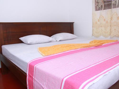 a bed with an orange blanket and pillows on it at Dilan Guest in Mirissa