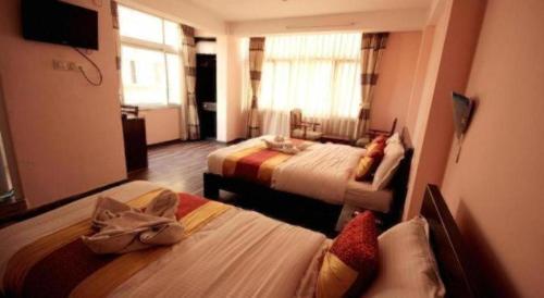 a hotel room with two beds and a television at De Hotel Veda in Kathmandu