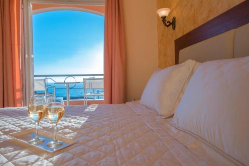 a bed with a glass of wine next to a window at Philoxenia in Ermones