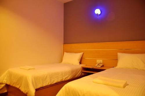 a room with two beds and a light on the wall at Hotel Economy Kapar in Kapar