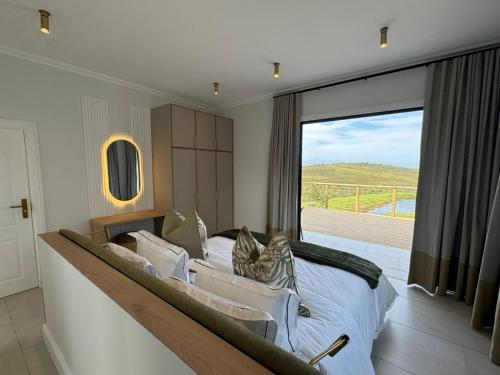 a bedroom with a large bed and a large window at Plettenvale Wines in Plettenberg Bay