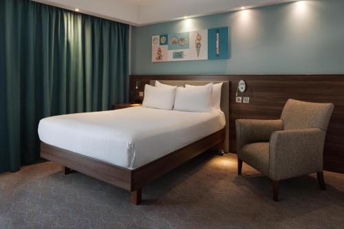 ボーンマスにあるハンプトン バイ ヒルトン ボーンマスの大きなベッドと椅子のある寝室