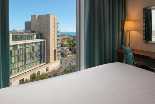ボーンマスにあるハンプトン バイ ヒルトン ボーンマスのベッドと街の景色が見える寝室