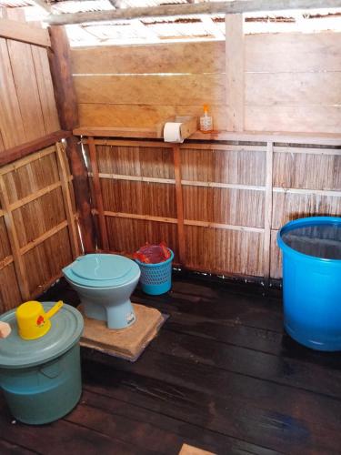 a bathroom with a toilet and buckets on a wooden floor at Batanta Panorama Homestay in Dayang