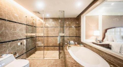 een badkamer met een bad, een wastafel en een bed bij Foshan Jubilee Hotel in Pingzhou