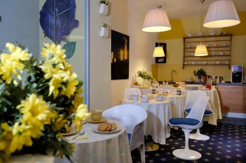 un ristorante con tavoli e sedie bianchi e fiori gialli di My Hotel Milano a Milano