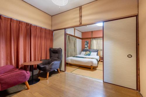 a bedroom with a bed and a chair and a table at ぱんだホステル三ノ輪 Panda Hostel Minowa in Wada