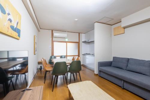 a living room with a couch and a table and chairs at ぱんだホステル三ノ輪 Panda Hostel Minowa in Wada