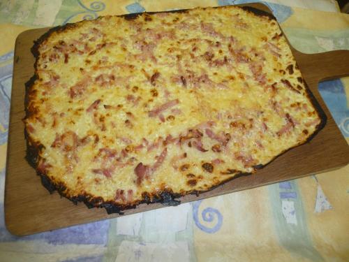 a large cheese pizza on a wooden cutting board at Relais du Klevener in Heiligenstein