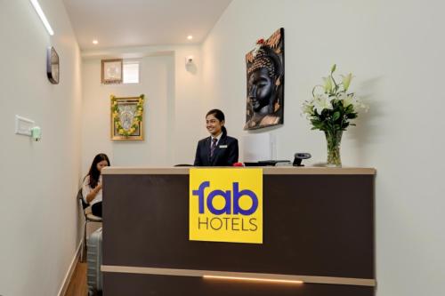 a woman standing behind a reception desk with a tolo hotel sign at FabHotel Sejour Royal in Chennai