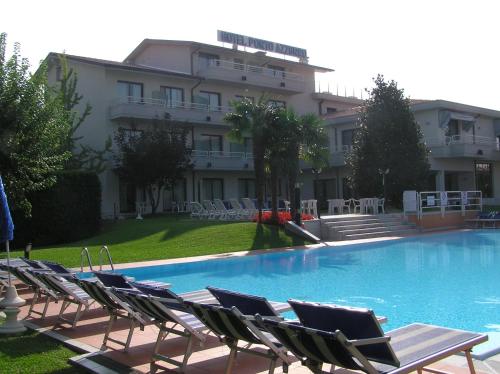 a swimming pool with lounge chairs and a building at Hotel Porto Azzurro in Sirmione
