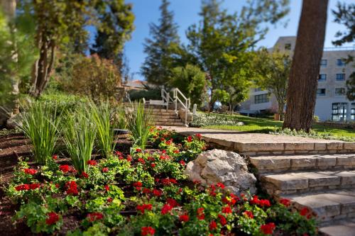 a garden with red flowers and stairs in a park at Ye'arim Hotel in Maale Hachamisha