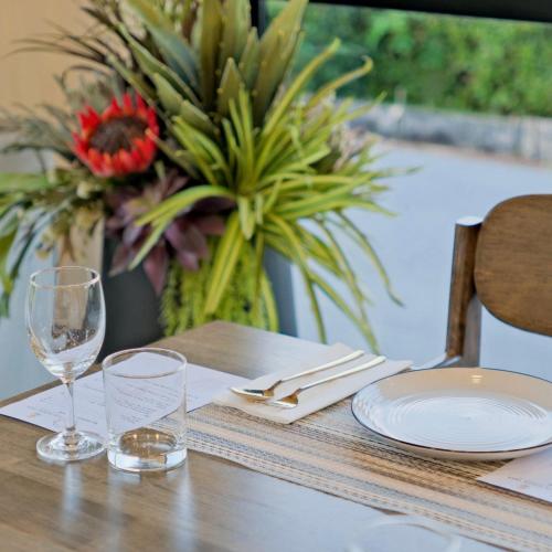 a wooden table with glasses and plates and a vase of flowers at Sun Moon Tree Resort & Recreation in Ban Khok Sung