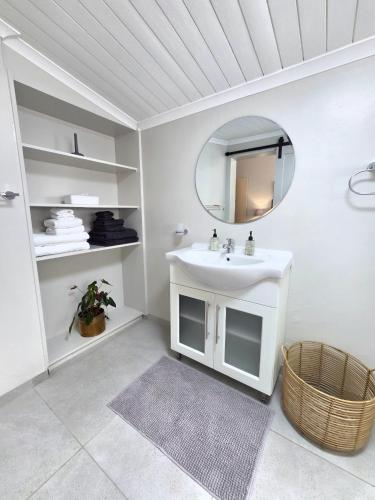 a white bathroom with a sink and a mirror at SleepINN at Dumont in Paarl