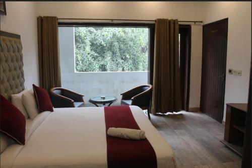 ein Schlafzimmer mit einem Bett und einem großen Fenster in der Unterkunft Khanna Residency in Neu-Delhi