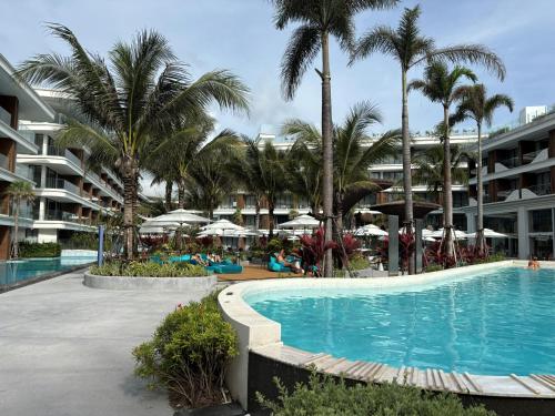 une piscine dans un complexe hôtelier avec des palmiers et des parasols dans l'établissement The Sunshine Beach Family Suite with Pool, à Layan Beach