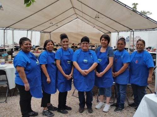a group of women in blue uniforms standing under a tent at Inn at Halona in Zuni