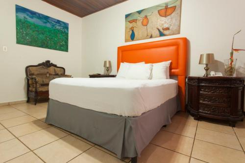 a bedroom with a large bed with an orange headboard at La Posada del Arcangel in Managua