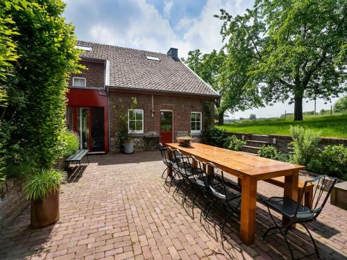 a wooden table and chairs in front of a house at Voeren Mansion with Garden in Voeren