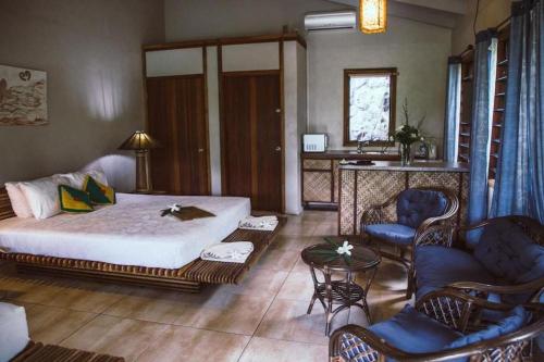 a bedroom with a bed and a couch and chairs at Le Manumea Hotel in Tiavi
