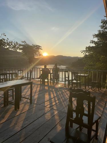 Dos personas sentadas en una terraza mirando la puesta de sol en Janh Ya Phone Guesthouse, en Pakbeng