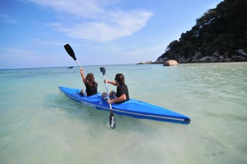two women are sitting on a blue kayak in the water at Flora Bay 1 in Perhentian Island
