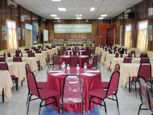 une grande salle de banquet avec des tables, des chaises et un tissu de table rouge dans l'établissement Flora Bay 1, aux Îles Perhentian