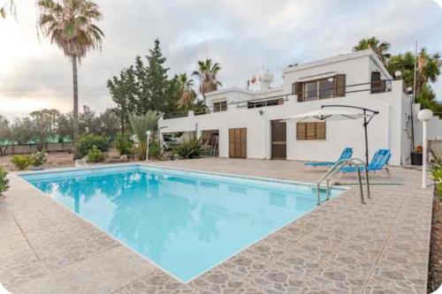 a house with a swimming pool in front of a house at Sun Wave Villa Sea View Retreat in Peyia