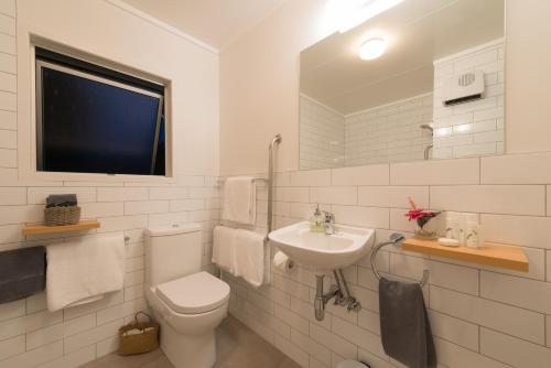 a white bathroom with a toilet and a sink at Stay Kerikeri in Kerikeri