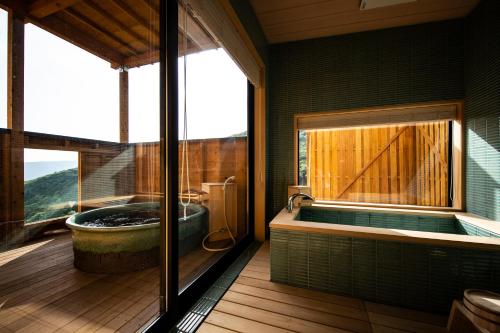 a bathroom with a tub and a large window at TOKI Resort HAKONE BETTEI in Hakone