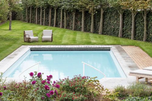 - une piscine dans une cour avec 2 chaises dans l'établissement De Pagode - A Serene Coastal Home with Pool, à Duinbergen