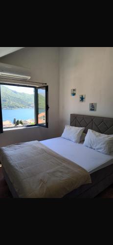 a bedroom with a large bed with a large window at Apartman Herceg Novi Capital in Kamenari