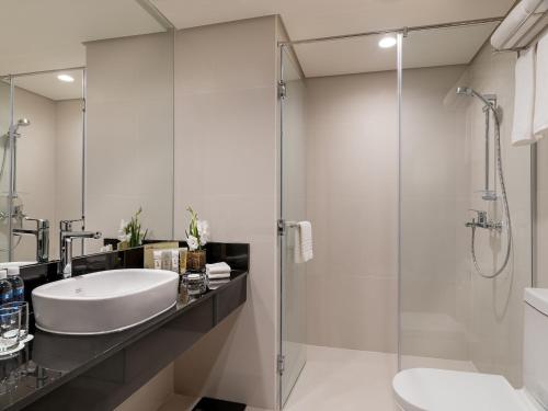 La salle de bains est pourvue d'un lavabo et d'une douche en verre. dans l'établissement Seda Atria, à Iloilo
