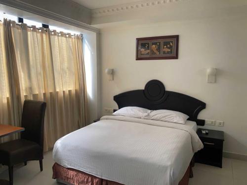 a bedroom with a bed and a chair and a window at Hotel O CHOTHY'S PARK in Trippapur
