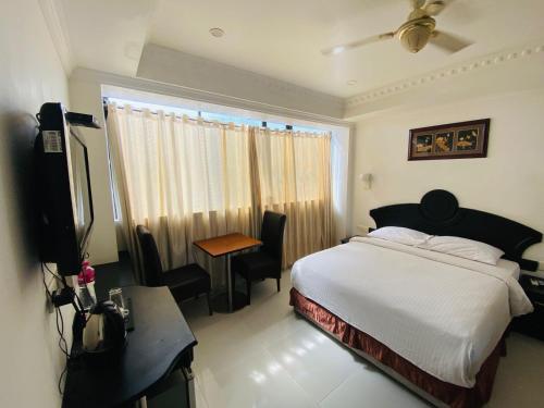 a bedroom with a bed and a desk and a window at Hotel O CHOTHY'S PARK in Trippapur