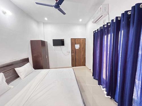 a room with a bed with blue curtains and a ceiling fan at Hotel O SGT University Road Formerly Budhera in Dhankot