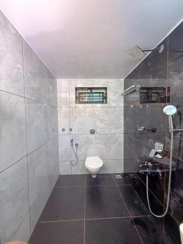 a bathroom with a shower and a toilet in it at Arcadia Homestay in Kāsarkod