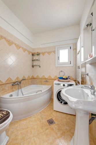 a bathroom with a tub and a sink and a toilet at Elysia House in Posidhonía