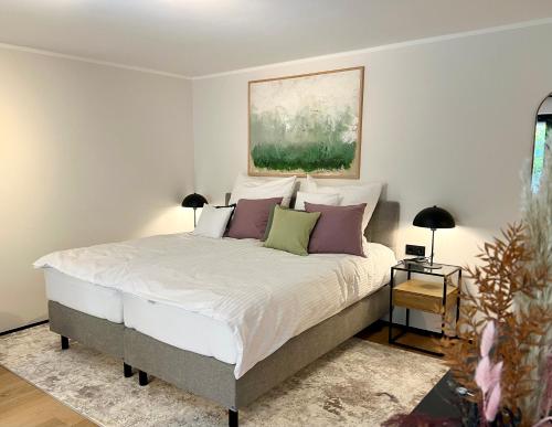 a bedroom with a bed with pillows and a painting at Pittino Gartensuite 03 in zweiter Seereihe Ammersee in Herrsching am Ammersee