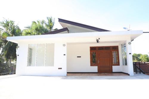 a small white house with a brown door at Naren Guest House in Kallady