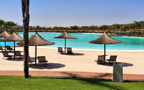 a pool with chairs and umbrellas on a beach at 2 Bed at the Blyde in Pretoria