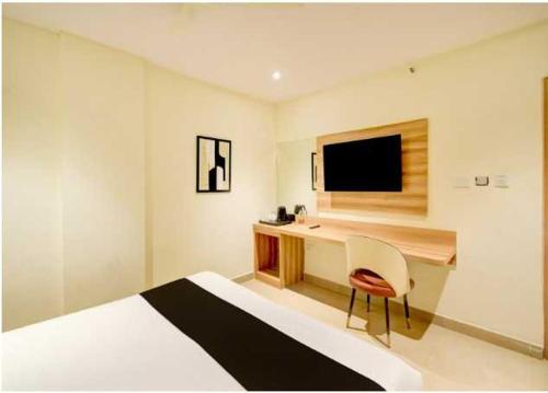 ein Schlafzimmer mit einem Bett und einem Schreibtisch mit einem Fernseher in der Unterkunft Collection O Mangalpalli Temple Hyderabad Formerly Royal Grand in Ibrāhīmpatan