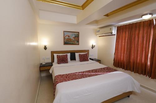 a hotel room with a bed and a window at Hotel Nahar Manchester Inn in Coimbatore