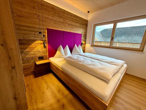 a bedroom with a large bed with a purple headboard at dein Dahoam Boutique Appartements in Gröbming