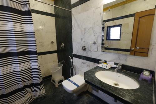a bathroom with a sink and a toilet and a mirror at Hotel Nahar Manchester Inn in Coimbatore