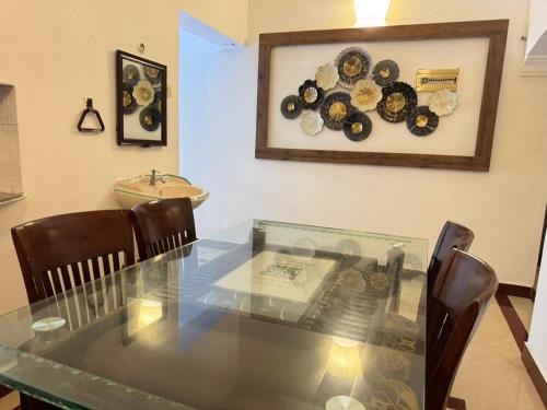 a glass table with chairs and a clock on the wall at De Pondy beachside Villa in Virāmpattinam