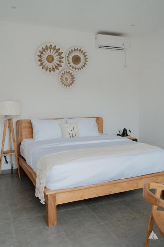 a bed in a room with a white wall at Skutik House in Tanah Lot