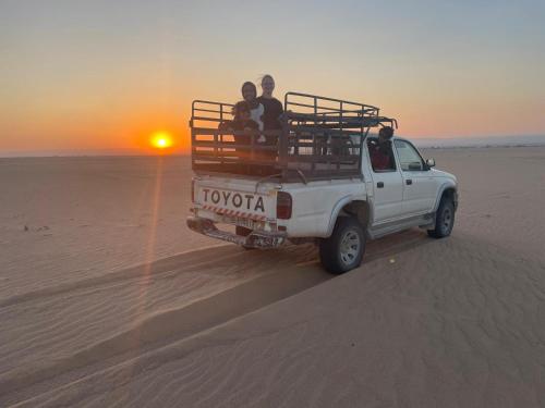Un groupe de gens qui roulent à l'arrière d'un camion dans le désert dans l'établissement Halfway motel, à An Namatah