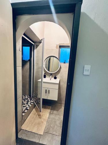 Ein Spiegel reflektiert ein Badezimmer mit Waschbecken. in der Unterkunft Enez Place in Gqeberha